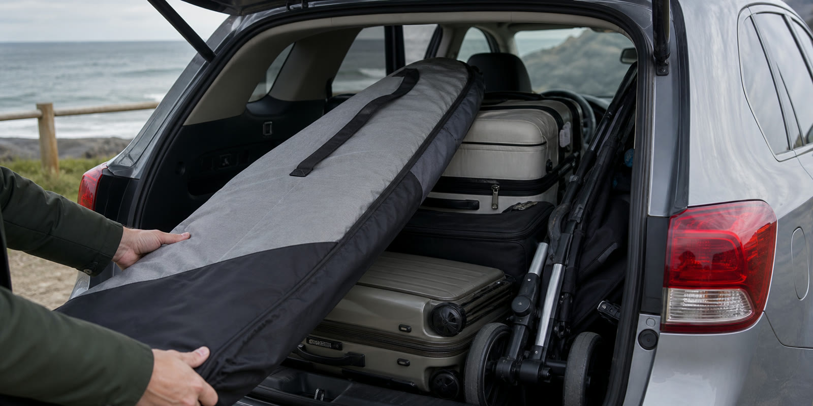 Planche de surf, poussette et valises chargées dans le coffre d’un véhicule